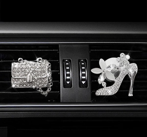 Close-up of sparkling diamond-encrusted purse and high heel car vent perfume clips