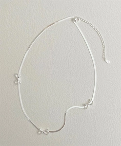 Detail of 925 sterling silver snake chain necklace featuring three elegant bow charms