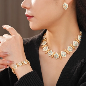 Detailed view of model wearing vintage gold enamel rhinestone necklace and earring set