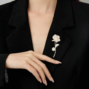 Elegant gold rose brooch with sparkling crystals and large pearl pendant on black suit