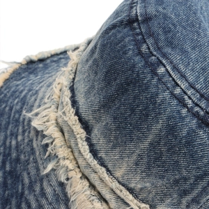Close-up of raw frayed edges and double stitching on blue washed denim bucket hat