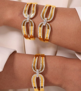 Détail d'un bracelet jonc entrelacé plaqué or 18k serti de cristaux sur le poignet