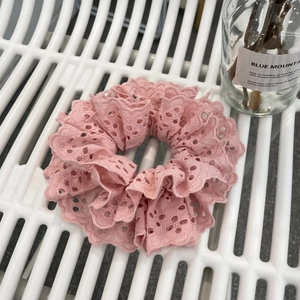 Elegant pink lace scrunchie with intricate embroidery on a white background