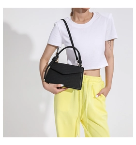 Close-up of black crossbody bag featuring vertical striped texture and envelope flap