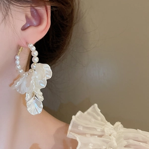 Close-up of pearl hoop earrings with white petal tassels on a model for a chic style