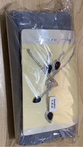 Dettaglio del set collana e orecchini a goccia blu scuro in confezione plastica