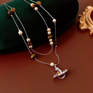 Detail shot of vintage pearl and tiger eye double layer Saturn pendant necklace on velvet