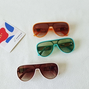 Fashion oversized pilot sunglasses in orange, green, and white on a textured background