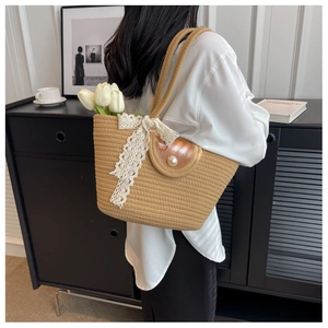 Detail of straw woven tote with brown leather flap, pearl button and white lace bow