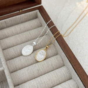 Detail of silver and gold oval shell necklaces with heart motifs on velvet padding