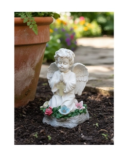 Detalle de estatua de ángel de resina blanca con cruz y base de flores en un jardín