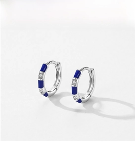 Macro shot of silver hoop earrings with blue enamel finish and sparkling zircon stones