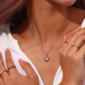 Macro detail of silver starburst pendant with white zircons and stacked gold rings