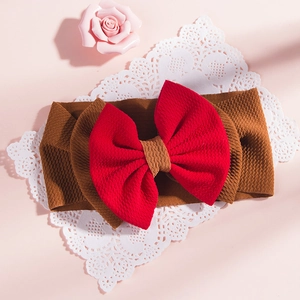 Detail of red bow on brown elastic crepe headband for babies on white lace and floral background