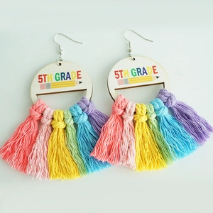 Close-up of wooden rainbow tassel earrings with 5th Grade text and pencil print