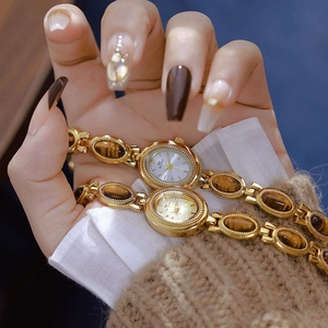 Detail shot of vintage gold link watch featuring tiger eye stone inlay and BS logo dial