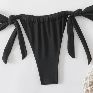 Dettaglio dello slip bikini nero con laccetti laterali e trama a pieghe in vita