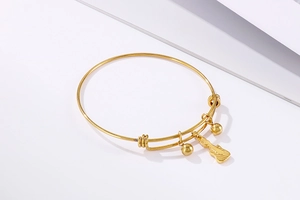 Detail of adjustable gold stainless steel bracelet with guitar and bead charms