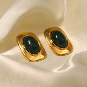 Détail de boucles d'oreilles ovales en or 18k avec pierres vert émeraude sur soie