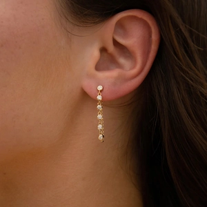 Close-up of elegant gold drop earrings with vertical round cubic zirconia on a model