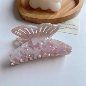 Detail of pink and white marble acetate butterfly hair claw clip on wooden tray