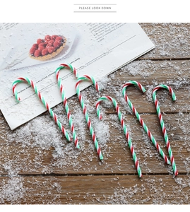 Set of 6 red, green, and white striped candy cane ornaments on dark wood with snow