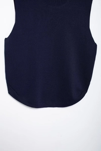 Detail of the navy blue knitted vest showing the curved hemline and fine knit texture