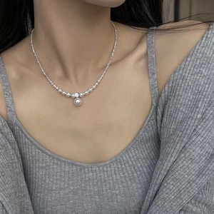 Elegant silver beaded necklace with a central pearl pendant shown on a model's neck