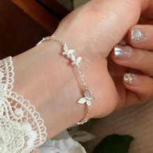 Close-up of double-layer silver bracelet with moonstone heart and butterfly charms