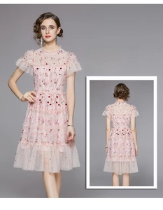 Vue détaillée des broderies florales sur robe en dentelle rose avec ourlet volanté