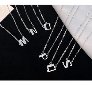 Macro detail of S925 silver alphabet pendants M to S with micro-pave cubic zirconia crystals