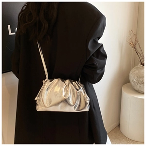 Silver metallic cloud bag with pleated texture shown on model in a stylish setting