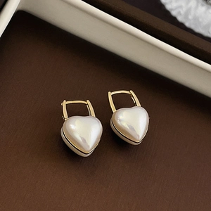 Vue macro des boucles d'oreilles cœur en plaqué or avec finition nacrée et fermoirs en U