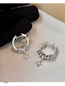 Close-up of silver hoop earring with zircon-studded rings and a star-shaped pendant