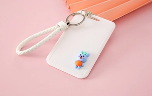 Detail of white cartoon rabbit card holder with woven wrist strap on orange background