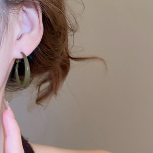 Close-up of model wearing olive green geometric resin hoop earrings with glossy finish