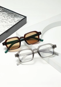 Close-up of retro square sunglasses in amber and transparent frames on white props
