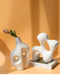 Macrodetail van witte matte keramische vazen met uitsparingen en een roze tulp
