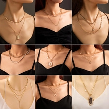 Detail of layered gold necklaces featuring coin, moon, and butterfly pendants for women