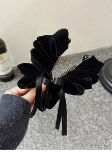 Detail shot of elegant black velvet bow hair claw clip held in hand with resin teeth view