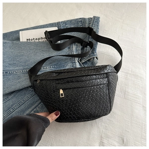 Detail of black woven crescent waist bag featuring a golden zipper and adjustable nylon strap