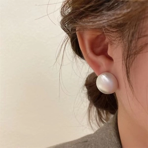 Élégantes boucles d'oreilles clous demi-perle blanche en argent 925 sur un mannequin