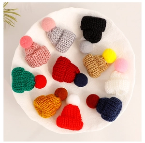Close-up of colorful mini knitted hats with pom-poms on a white tray for DIY crafts
