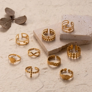 9-piece gold sun cross and evil eye adjustable rings set on stone display tray