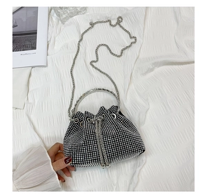 Close-up of sparkling silver rhinestone bucket bag with metal chain strap and ring handle