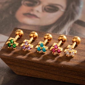 Five gold stainless steel stud earrings set with colorful round zirconias on wooden block