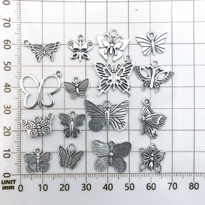 Detailed view of Tibetan silver butterfly pendants on a measuring mat with mm scale