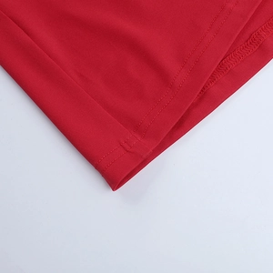 Gros plan sur la couture double aiguille précise de l'ourlet de la robe rouge