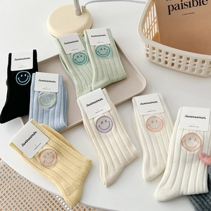 Colorful combed cotton mid-calf socks with smiley embroidery in a minimalist setup