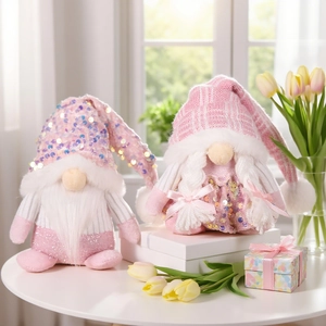 Pink sequin Christmas gnome dolls with knitted hats on table for holiday decoration